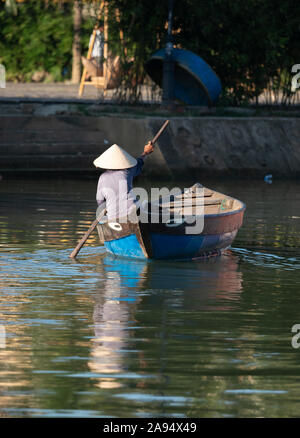 Une femme de l'œil en bois bateau dans Hoi An, Vietnam avec l'escalier menant à l'eau dans l'arrière-plan. Banque D'Images