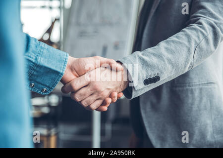 Startupers masculins travaillant ensemble au comité permanent office shaking hands Banque D'Images
