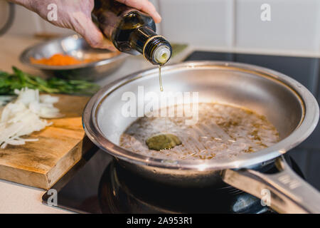 Photo de l'atmosphère de la cuisine dans le style rural - mains rugueuses au travaux de cuisine - de l'huile dans la casserole Banque D'Images