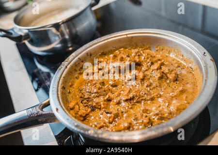 Tranches de filet de poulet, oignons frits et les carottes dans une sauce à la crème dans une casserole - close-up - cuisine maison Banque D'Images