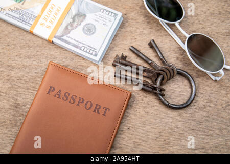 Bande de différentes clés, passeport et de l'argent sur une table en bois. Nouveaux logements, propriété et concept de prêt hypothécaire Banque D'Images