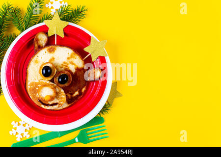 Kid's Christmas deer aliments comestibles art. sur plaque rouge avec des étoiles au lieu de cornes comme petit-déjeuner de Noël. Cute deer fait de crêpe et de baies. Copier l'espace. Banque D'Images