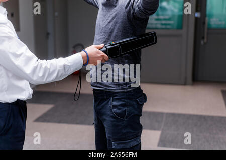 Protection avec un détecteur de métal contrôler un homme d'armes et objets de métal avant d'entrer dans le ministère du trésor Banque D'Images