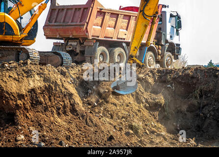 La pelle hydraulique charge l'excavation sur le tombereau. Équipement de construction lourd composé d'une flèche, d'un balancier ou d'un bras, d'un godet et d'une cabine Banque D'Images