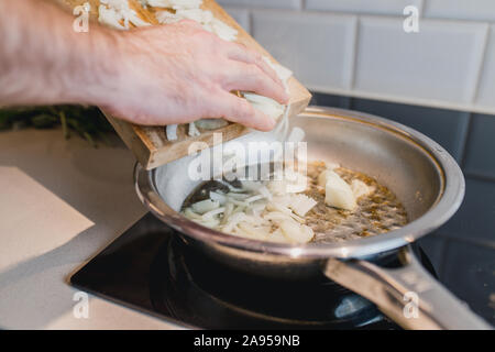 Mettre les rondelles d'oignons dans une poêle avec de l'huile bouillante - close-up - cuisine maison Banque D'Images