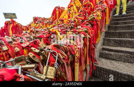 Huashan, Chine - Août 2019 : Mémorial symbolique religieuse et rubans rouges et cadenas verrouillé lié à des obstacles le long du chemin de Huashan Banque D'Images