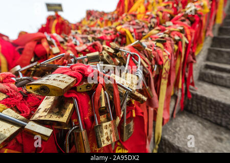 Huashan, Chine - Août 2019 : Mémorial symbolique religieuse et rubans rouges et cadenas verrouillé lié à des obstacles le long du chemin de Huashan Banque D'Images