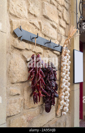 Ristras de gousses de poivre et l'ail sur le mur de pierre Banque D'Images