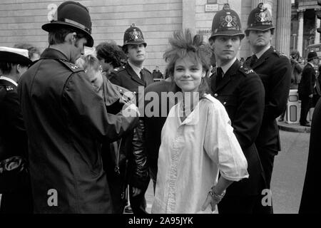 Teen girl Punk des années 80, à l'arrêt de la ville de Londres Royaume-uni 27 septembre 1984 démonstration. Protestation contre le capitalisme anti banquiers 80s en Angleterre. La réalisation d'une police d'arrêter et de recherche sur les jeunes. Girl Friend posing. HOMER SYKES Banque D'Images