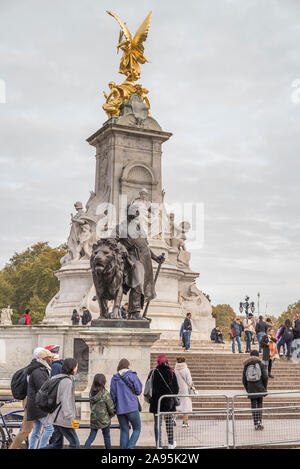 Portrait tourné de touristes britanniques visitant la statue du Mémorial de la Reine Victoria directement en dehors du palais de Buckingham, Londres, Royaume-Uni, le jour de novembre froid. Banque D'Images