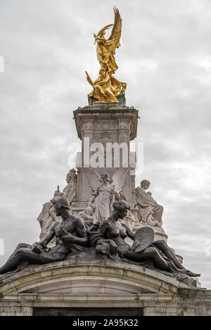 Portrait, angle bas près du Queen Victoria Memorial à l'extérieur de Buckingham Palace, Londres, Royaume-Uni; statue de marbre Justice (face au Green Park) sur la vue. Banque D'Images