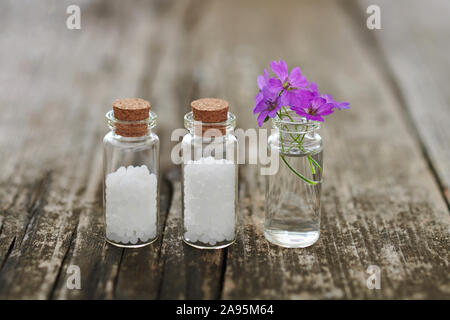 Les granules homéopathiques dans de petites fioles de verre et de petites fleurs roses. Banque D'Images