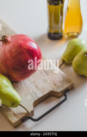 Les poires fraîches, huile d'olive et la grenade dans la cuisine sur une planche de bois de coupe - alimentation saine Banque D'Images