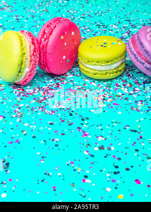 Cake macaron macaron ou sur fond bleu turquoise, de confettis, biscuits de couleur, carte de fête, selective focus Banque D'Images