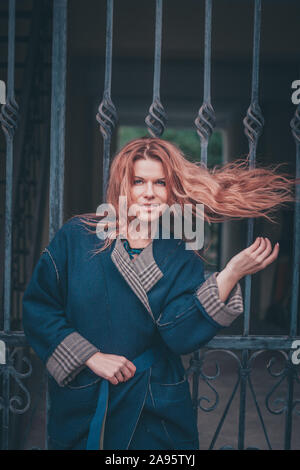 Belle rousse belle femme dans un élégant manteau long jette les cheveux épais sur l'épaule Banque D'Images