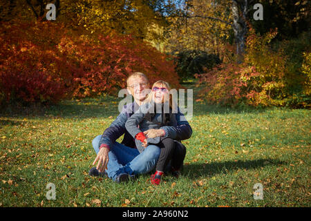 Papa joue avec sa fille dans le parc de l'automne. Banque D'Images