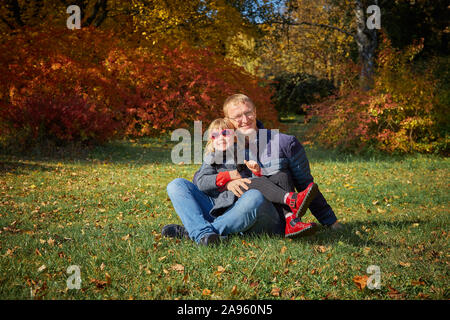 Papa joue avec sa fille dans le parc de l'automne. Banque D'Images