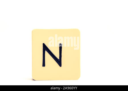 Lettre N foncé sur fond jaune pâle bloc carré isolé sur fond blanc Banque D'Images