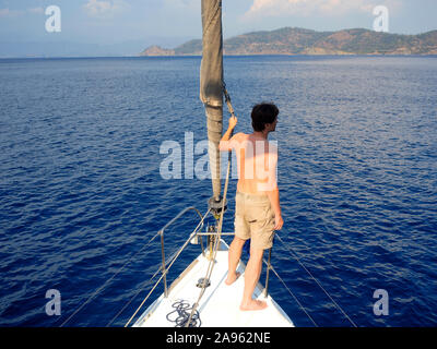 Regarder au-delà de l'horizon. l'homme en short se dresse sur la plate-forme près de la voile, de la voile et le yachting, concept. Guy sur un yacht voyage. Banque D'Images