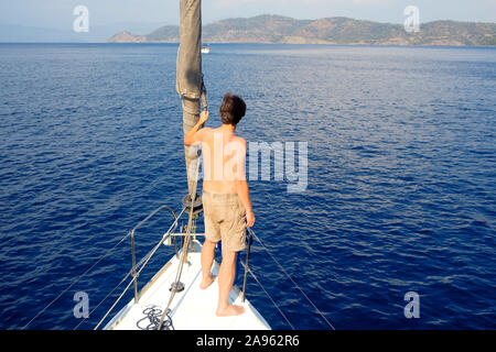 Regarder au-delà de l'horizon. l'homme en short se dresse sur la plate-forme près de la voile, de la voile et le yachting, concept. Guy sur un yacht voyage. Banque D'Images