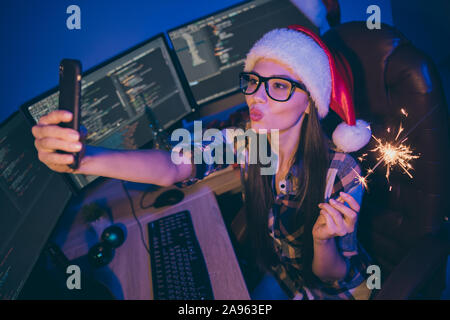 Photo de bourreau de travail codeur dame nuit rencontrez newyear office tenir téléphone sparkler en tenant vos autoportraits baisers air envoyer boire du vin porter chapeau de Père Noël Banque D'Images