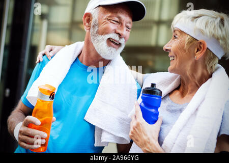 Mature couple boit de l'eau pour refaire le plein d'énergie et d'hydrater Banque D'Images