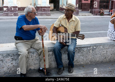 Un couple d'hommes locaux sont assis sur des sièges en marbre sur le Passeo Del Prado, un long boulevard de la Havane Cuba. Le Boulevard, bordé de lions de bronze et mar Banque D'Images