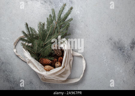 Zéro déchets concept de Noël. Décoration naturelle Chirsmas, pommes de pin et des branches dans un sac de linge. Mise à plat, vue du dessus. Banque D'Images