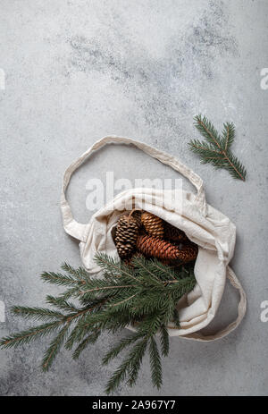 Zéro déchets concept de Noël. Décoration naturelle Chirsmas, pommes de pin et des branches dans un sac de linge. Mise à plat, vue du dessus. Banque D'Images