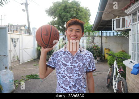 Adolescent qui aime le basket-ball puis il sourit, asian teenage boy holding a ball, teen boy, basket-ball garçons, jeune homme baskketball, hommes basketbal Banque D'Images