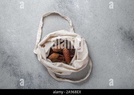 Zéro déchets concept de Noël. Décoration naturelle Chirsmas, pommes de pin et des branches dans un sac de linge. Mise à plat, vue du dessus. Banque D'Images