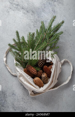 Zéro déchets concept de Noël. Décoration naturelle Chirsmas, pommes de pin et des branches dans un sac de linge. Mise à plat, vue du dessus. Banque D'Images