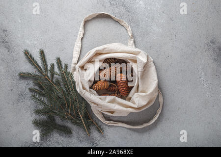 Zéro déchets concept de Noël. Décoration naturelle Chirsmas, pommes de pin et des branches dans un sac de linge. Mise à plat, vue du dessus. Banque D'Images