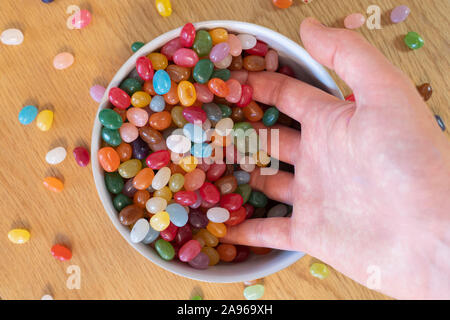 Un écopage de jelly beans dans un bol rempli de bonbons. Concept, la dépendance à des bonbons, des sucreries, des bonbons, des plaisirs de la vie Banque D'Images