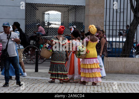 Un trio de femmes cubaines habillé en robe coloniale aux couleurs vives, prêts à poser pour des photographies touristiques, parfois avec de gros cigares dans leur bouche. Banque D'Images