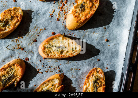 Fromage Parmesan ail tranches de pain sur une feuille de papier cuisson un plat à four. Des petits. En-cas sain organique. Banque D'Images