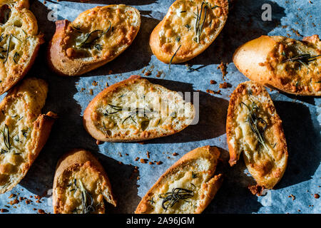 Fromage Parmesan ail tranches de pain sur une feuille de papier cuisson un plat à four. Des petits. En-cas sain organique. Banque D'Images