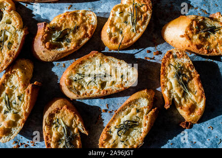 Fromage Parmesan ail tranches de pain sur une feuille de papier cuisson un plat à four. Des petits. En-cas sain organique. Banque D'Images