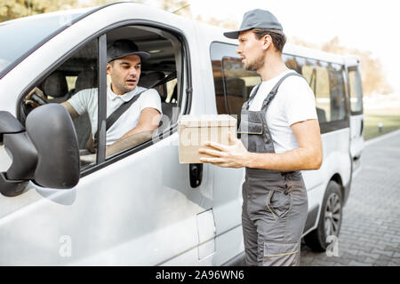 Les employés de l'entreprise de livraison en uniforme de la livraison des marchandises par camion, véhicule mover avec parcelle à parler avec un pilote automobile Banque D'Images
