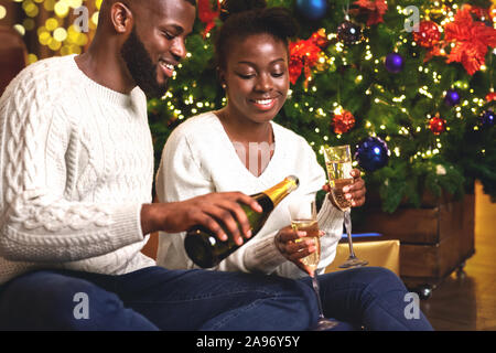 Happy african american couple toasting with New Year's Eve, célébrer les vacances d'hiver à la maison ensemble. Banque D'Images