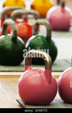 Kettlebells ou coulé les boules en acier avec poignée de diverses couleurs et poids sur plancher du gymnase. Sports, l'entraînement fonctionnel et l'équipement. Banque D'Images