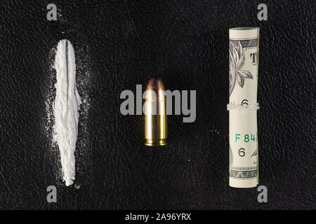 Une ligne de cocaïne en poudre, un seul 9 mm bullet et dollar bill faire défiler. Maquette conceptuelle de drogue illégale, la traite, la guerre contre la drogue. Banque D'Images