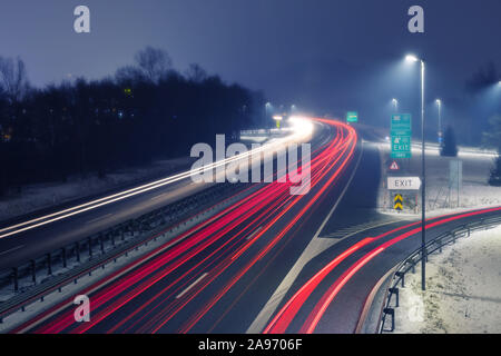 L'autoroute dans la nuit brumeuse avec sentiers lumineux de la lumière de trafic entrant et sortant. Les transports, l'urbanisme, de la circulation et de l'infrastructure des concepts. Banque D'Images