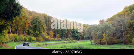 Voiture sur route près de la forêt aux couleurs vives en Eifel allemand au cours de l'automne Banque D'Images