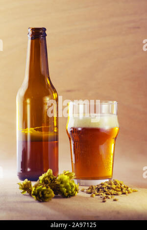 Bouteille et verre de bière avec l'orge et le houblon sur fond de bois. La brasserie de la bière artisanale, des boissons alcoolisées et des concepts. Banque D'Images
