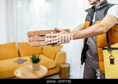 Courrier professionnel en uniforme holding boîtes à pizza, la livraison de nourriture accueil Banque D'Images