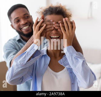 Rêves venir vrai. Happy Afro Mari couvrant les yeux de sa femme avant de montrer de nouvelles Home Standing Piscine. Selective Focus Banque D'Images