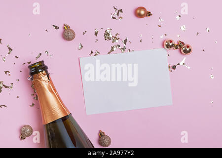 Carte de papier vierge mock-up sur le fond rose avec bouteille de champagne et confettis d'or Banque D'Images
