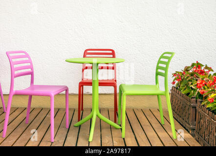 Quatre chaises colorées et une table à côté du mur blanc Banque D'Images