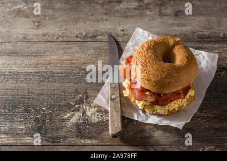 Sandwich Bagel dalle avec bacon, oeufs et fromage sur la table en bois. Copy space Banque D'Images